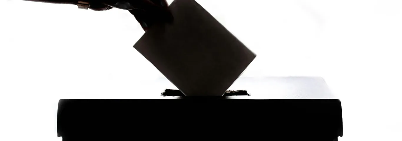 photo of hand casting a ballot
