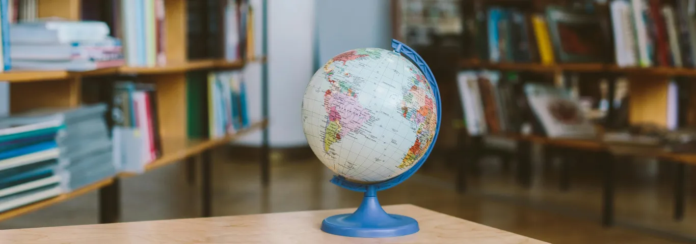 a photo graph of a small globe with a library in the background