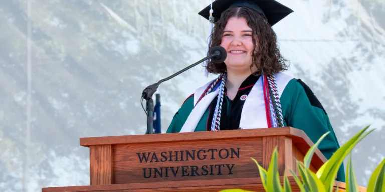 Mia Kouveliotes, AB ‘26, speaks at the 2026 College of Arts & Sciences Recognition Ceremony, May 14. As a student ambassador for the Public Health & Society program in Arts & Sciences, Kouveliotes helped shape curricular pathways and communicate its mission to prospective students. (Photo: Sean Garcia/WashU)