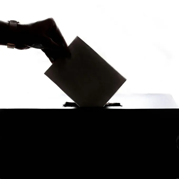 "photo of hand casting a ballot"