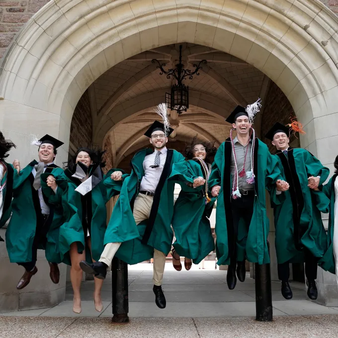 Photo of a group of WashU graduates gleefully jumping into the air together