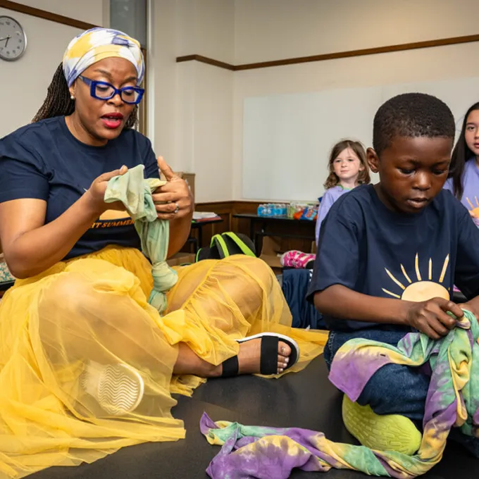 Juliet Iwelunmor leads campers in a mindfulness exercise designed to relieve stress and anxiety by wrapping themselves in tie-dyed cloth handmade in Nigeria. (Photo: Carol Green/WashU)
